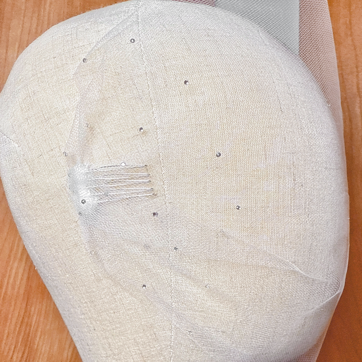 Close-up view of the sparkling rhinestone accents on a sheer tulle bandeau wedding veil.