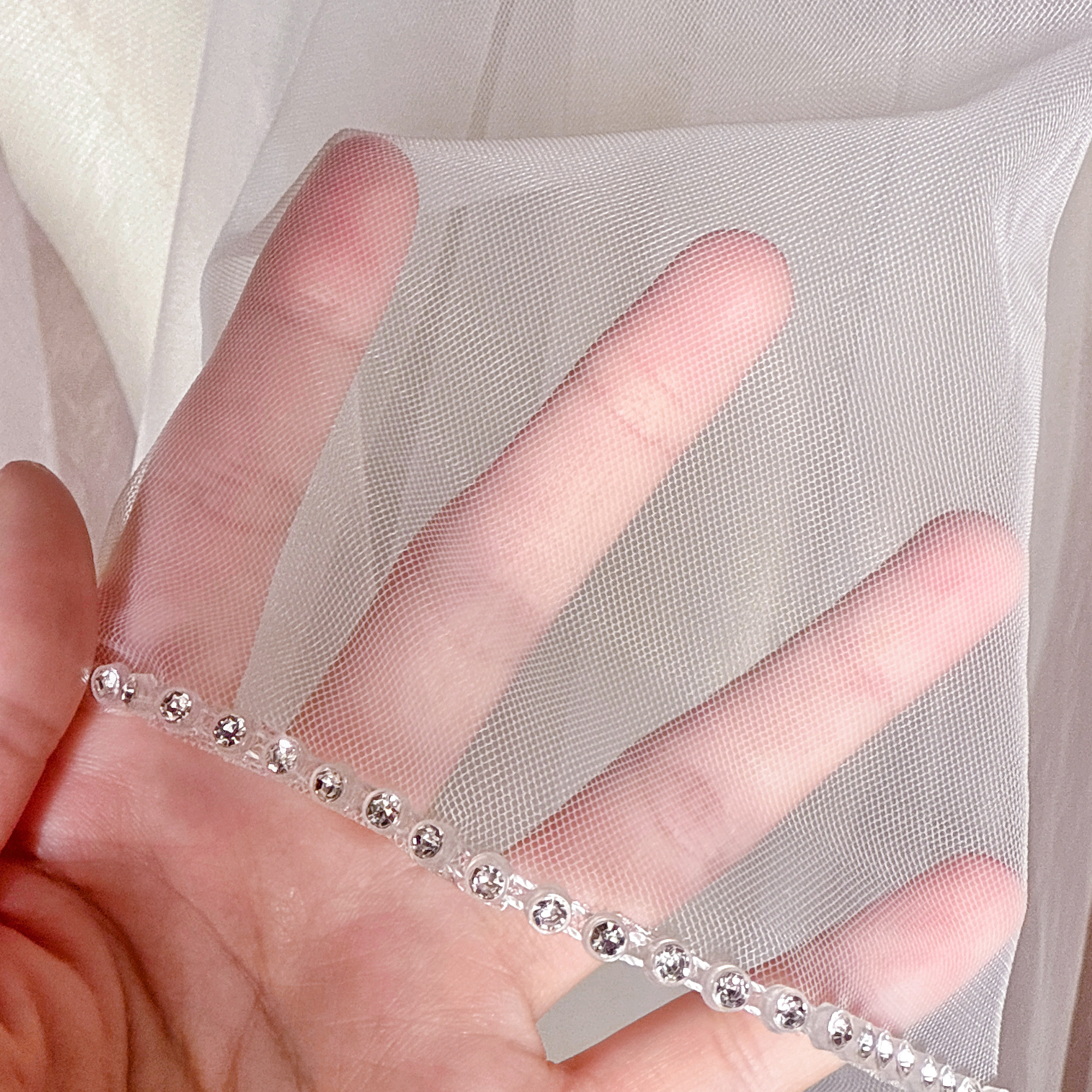 Macro close-up shot showing the detailed rhinestone edge craftsmanship on a two-tier cathedral length wedding veil.