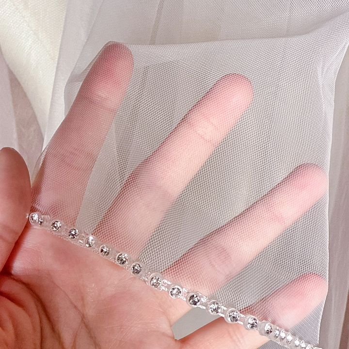 Macro close-up shot showing the detailed rhinestone edge craftsmanship on a two-tier cathedral length wedding veil.
