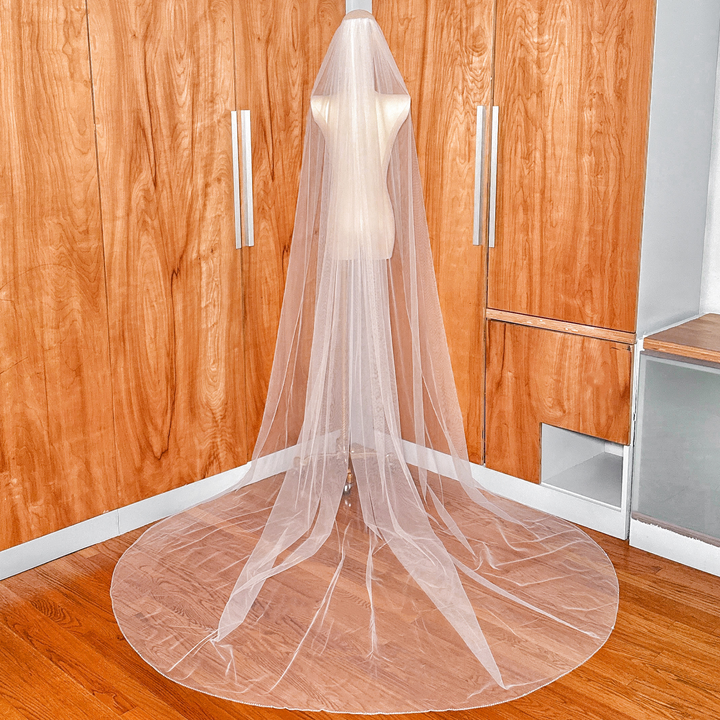 Long elegant cathedral length rhinestone edge wedding veil cascading down a display mannequin.