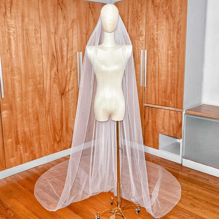 Cathedral length rhinestone edge wedding veil displayed on a bridal mannequin.