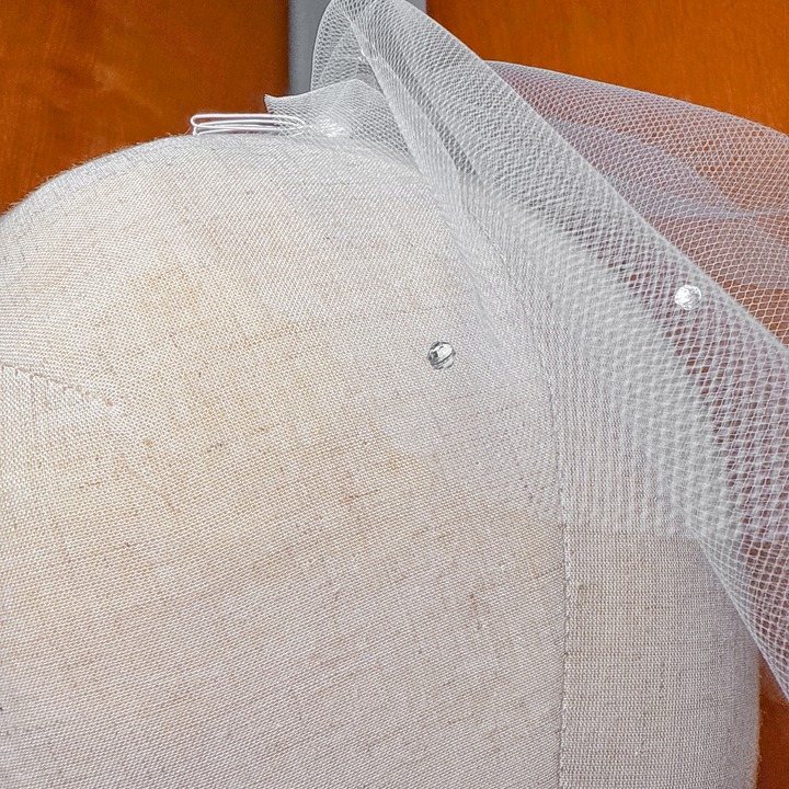 Close-up of a mini tulle birdcage wedding veil with scattered rhinestones showing fabric detail.