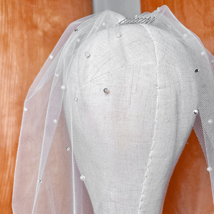 Close-up detail of hand-stitched rhinestones and pearls on a tulle birdcage wedding veil.