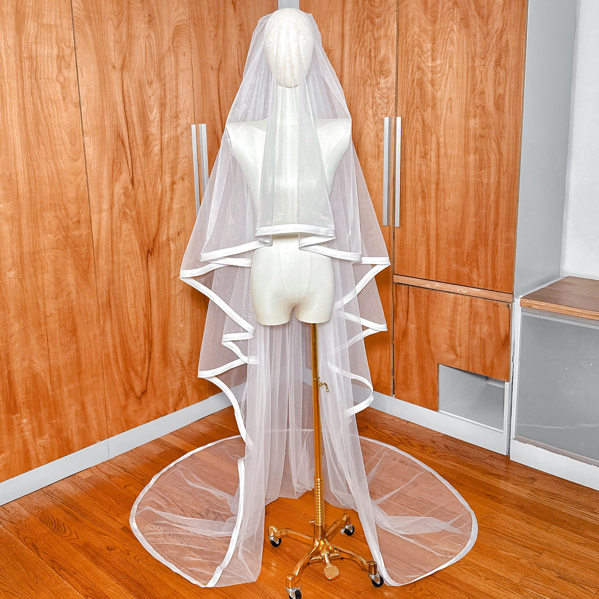 1 inch ribbon edge cathedral length wedding veil with a blusher draped on a mannequin.