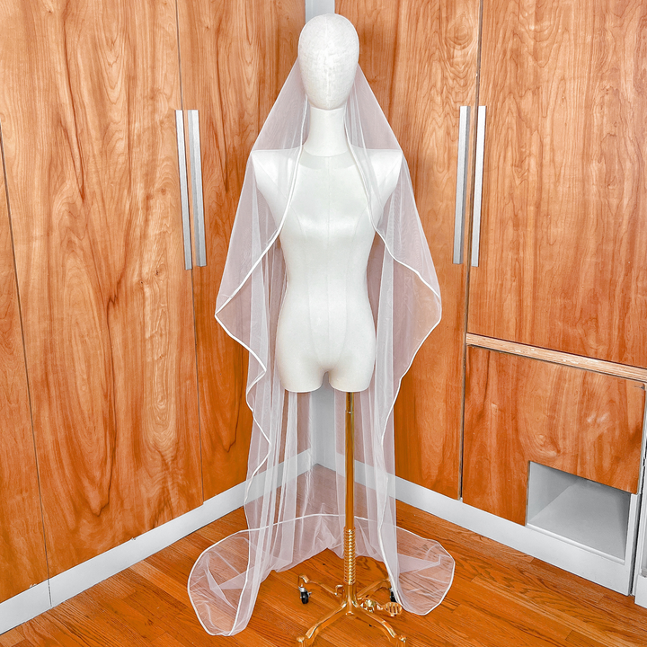 Ivory ribbon trim wedding veil made of soft tulle displayed on a bridal mannequin.