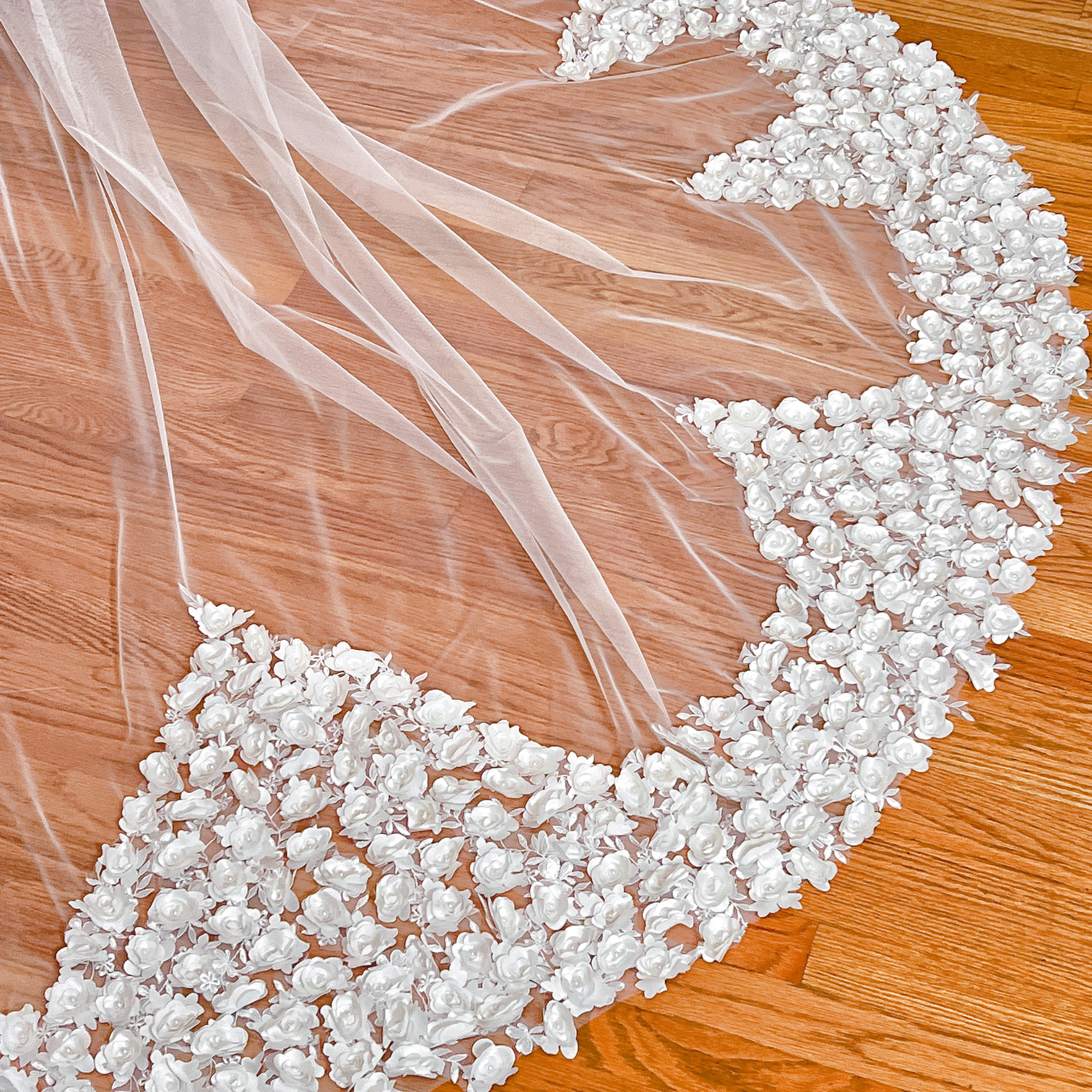 Close-up of the intricate 3D floral embroidery on a romantic cathedral-length wedding veil styled on a mannequin.