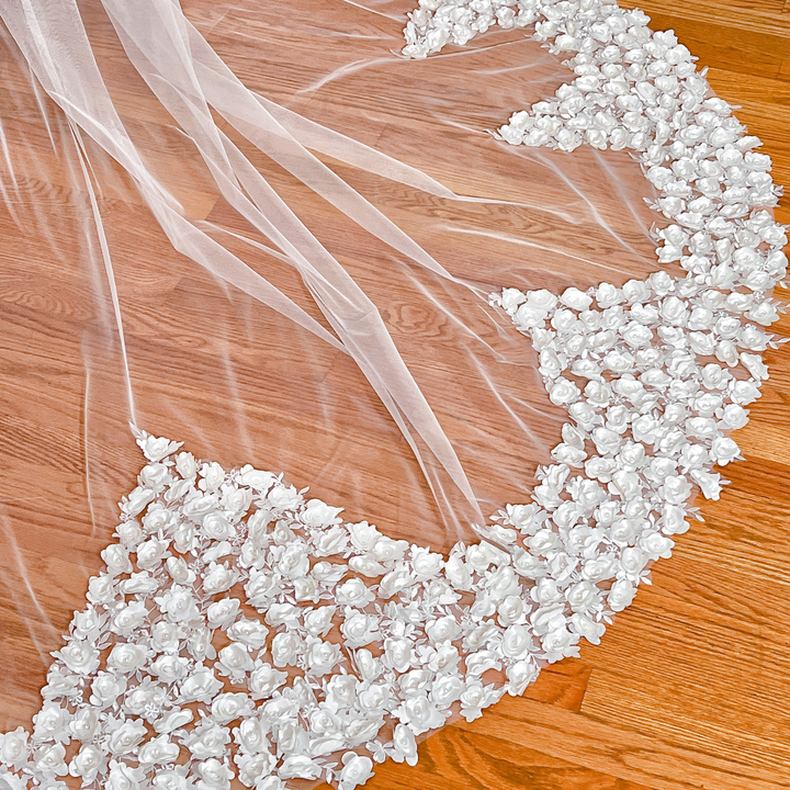 Close-up of the intricate 3D floral embroidery on a romantic cathedral-length wedding veil styled on a mannequin.