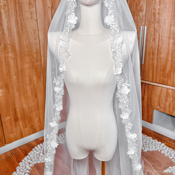 Texture of a romantic 3D flower wedding veil with a soft cathedral-length drape, presented on a mannequin.