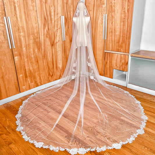 Full back view of a royal cathedral length floral lace mantilla wedding veil draped elegantly over a mannequin to show the dramatic train.