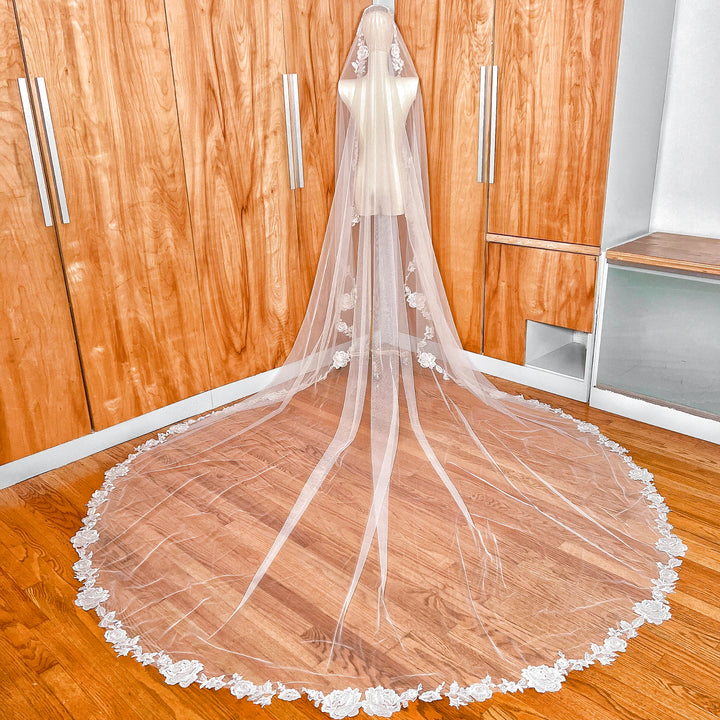 Full back view of a royal cathedral length floral lace mantilla wedding veil draped elegantly over a mannequin to show the dramatic train.