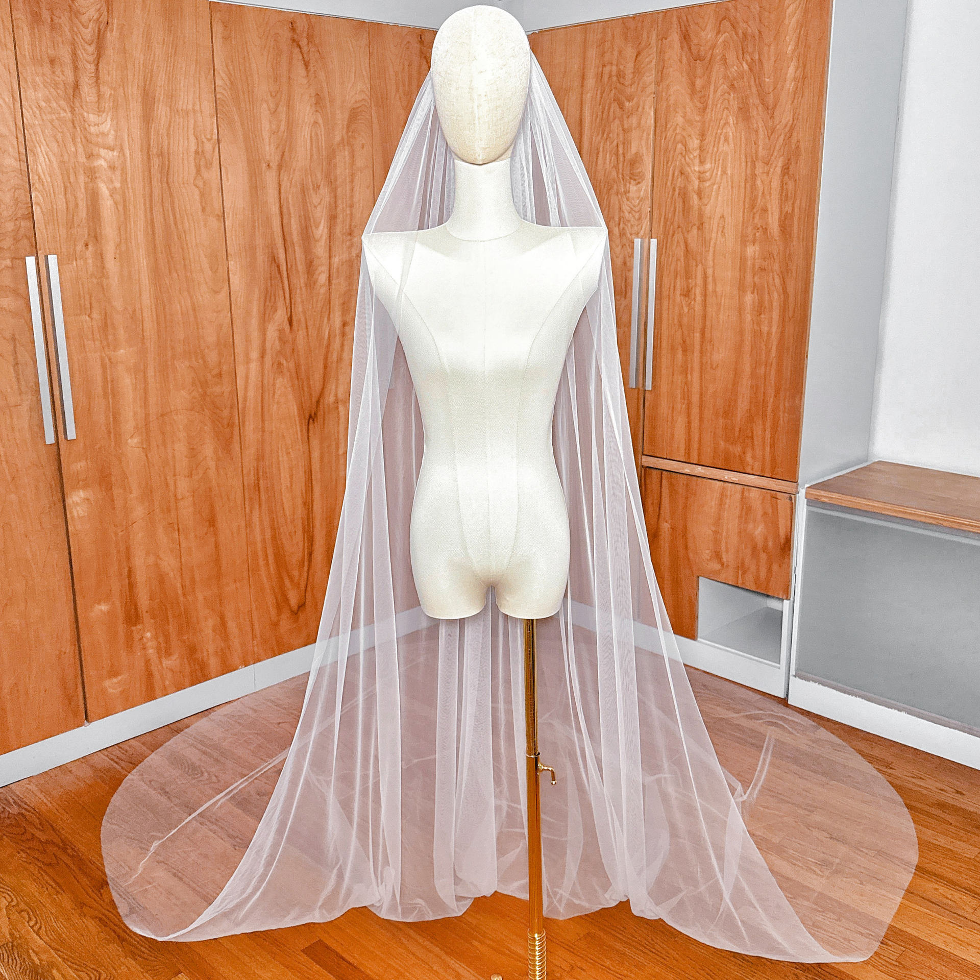 Full-length view of a Royal Cathedral Tulle Wedding Veil with a clean raw edge flowing from a mannequin.