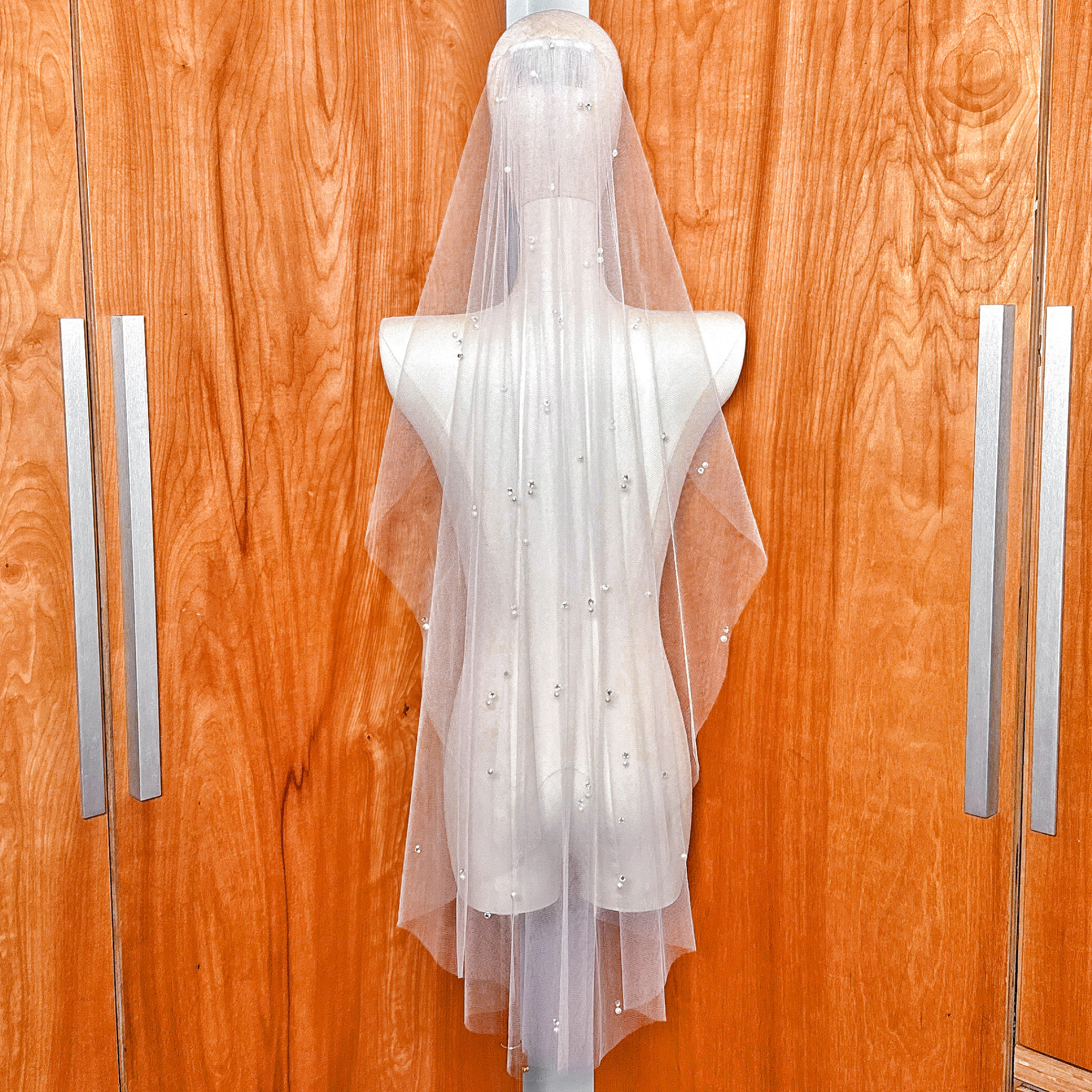 The sheer, lightweight quality of the scattered pearl and rhinestone wedding veil in fingertip length.
