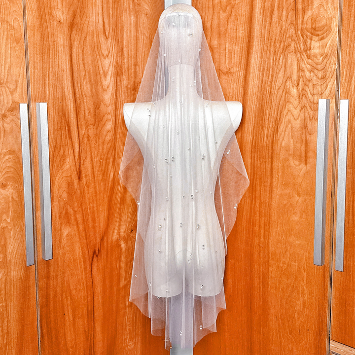 The sheer, lightweight quality of the scattered pearl and rhinestone wedding veil in fingertip length.