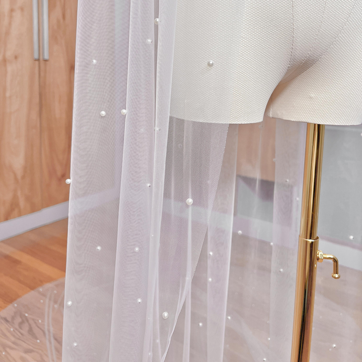 Close-up detail of hand-placed pearls scattered across high-transparency soft Italian tulle.