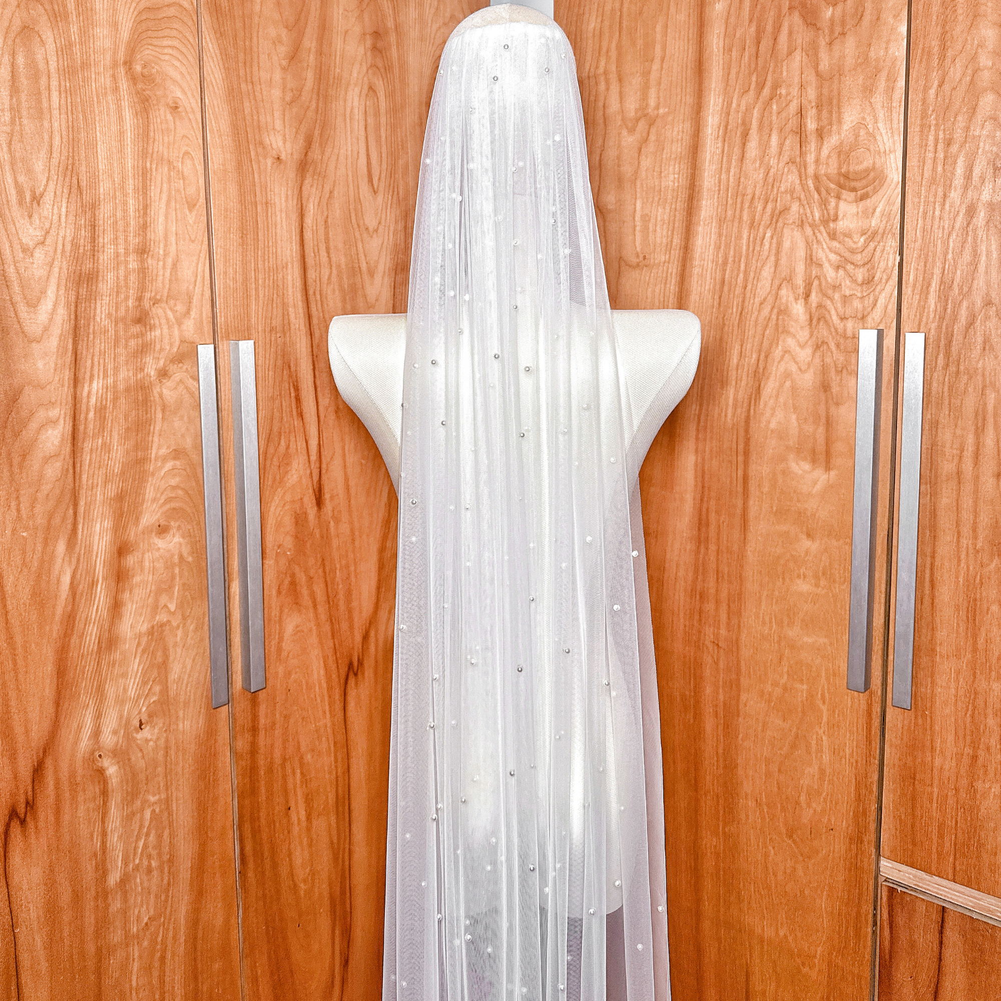 Silver bridal comb attachment on a single-tier cathedral wedding veil with scattered pearl accents.