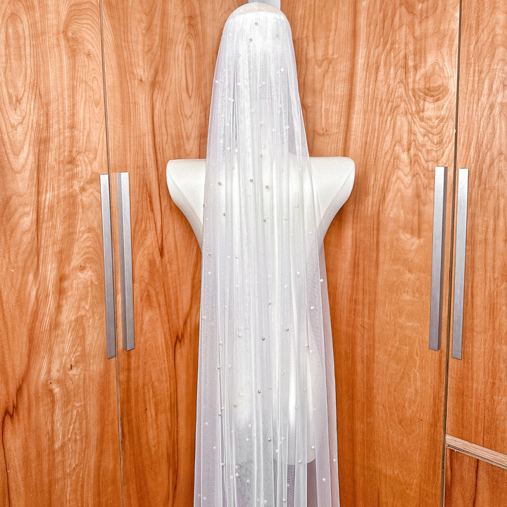 Silver bridal comb attachment on a single-tier cathedral wedding veil with scattered pearl accents.