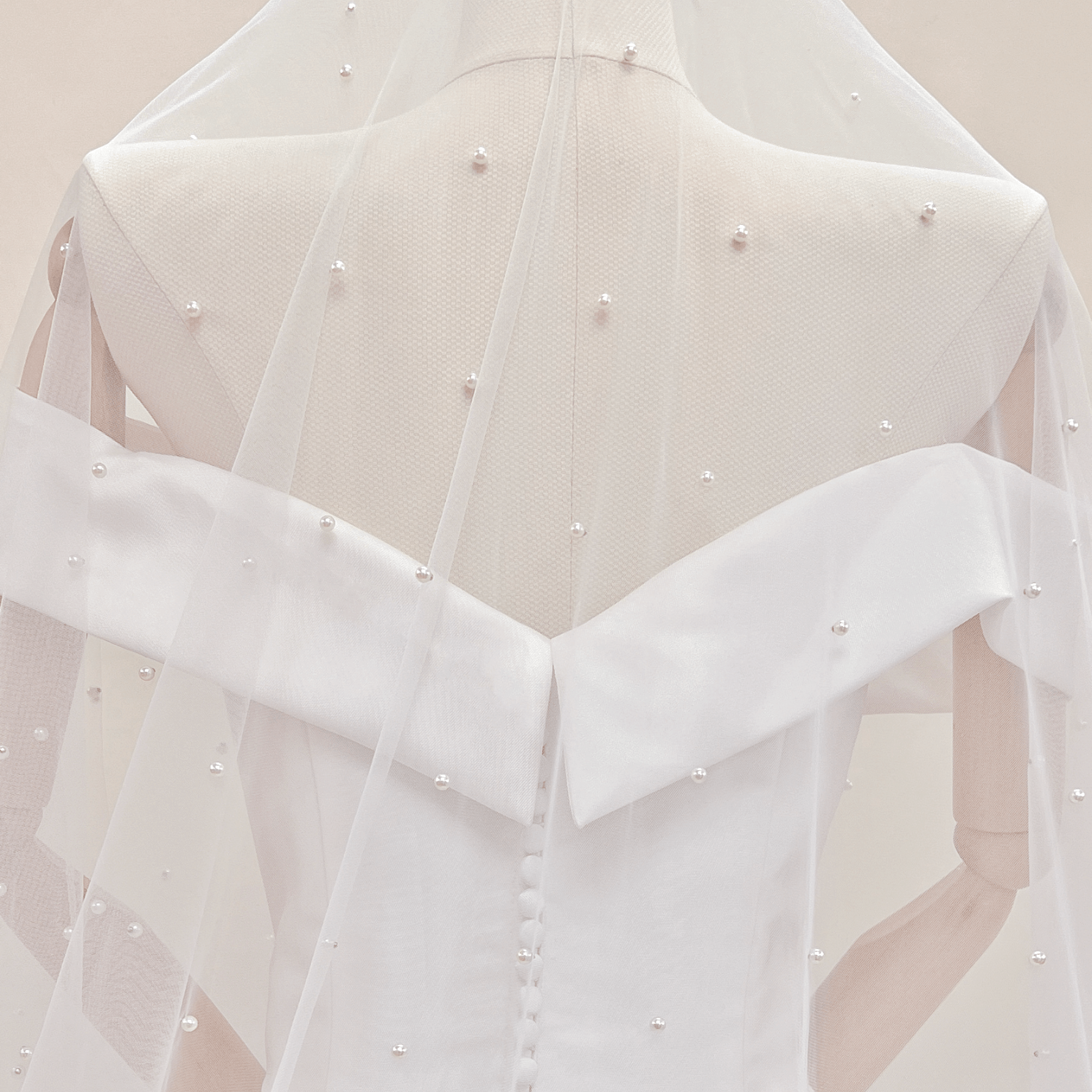 Detailed texture shot of various sized pearls scattered on an ivory cathedral bridal veil.