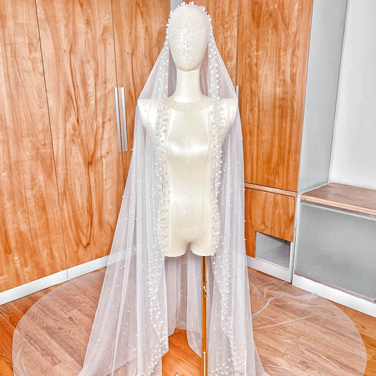 Front view of a cathedral length scattered pearl edge mantilla wedding veil draped over a bridal mannequin.