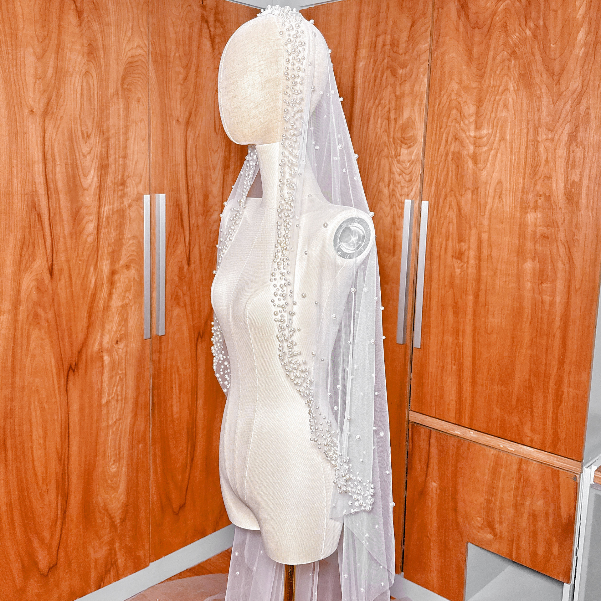 Cathedral length scattered pearl edge mantilla wedding veil draped over a mannequin to show full lace and pearl detail.