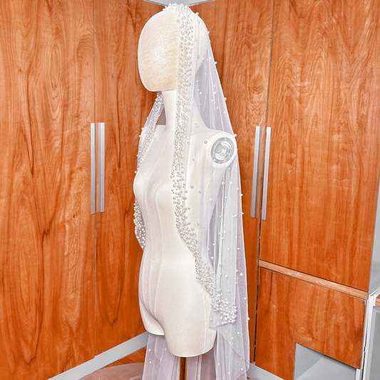 Cathedral length scattered pearl edge mantilla wedding veil draped over a mannequin to show full lace and pearl detail.