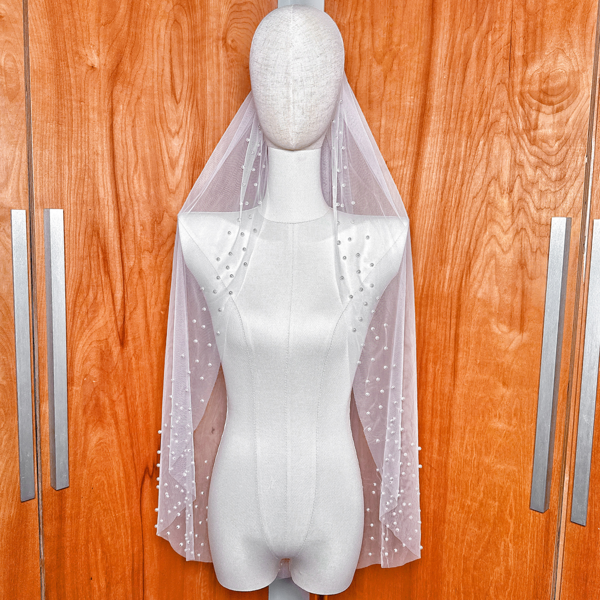 A fingertip length scattered pearl edge wedding veil draped elegantly to show the delicate pearl detailing along the hem.
