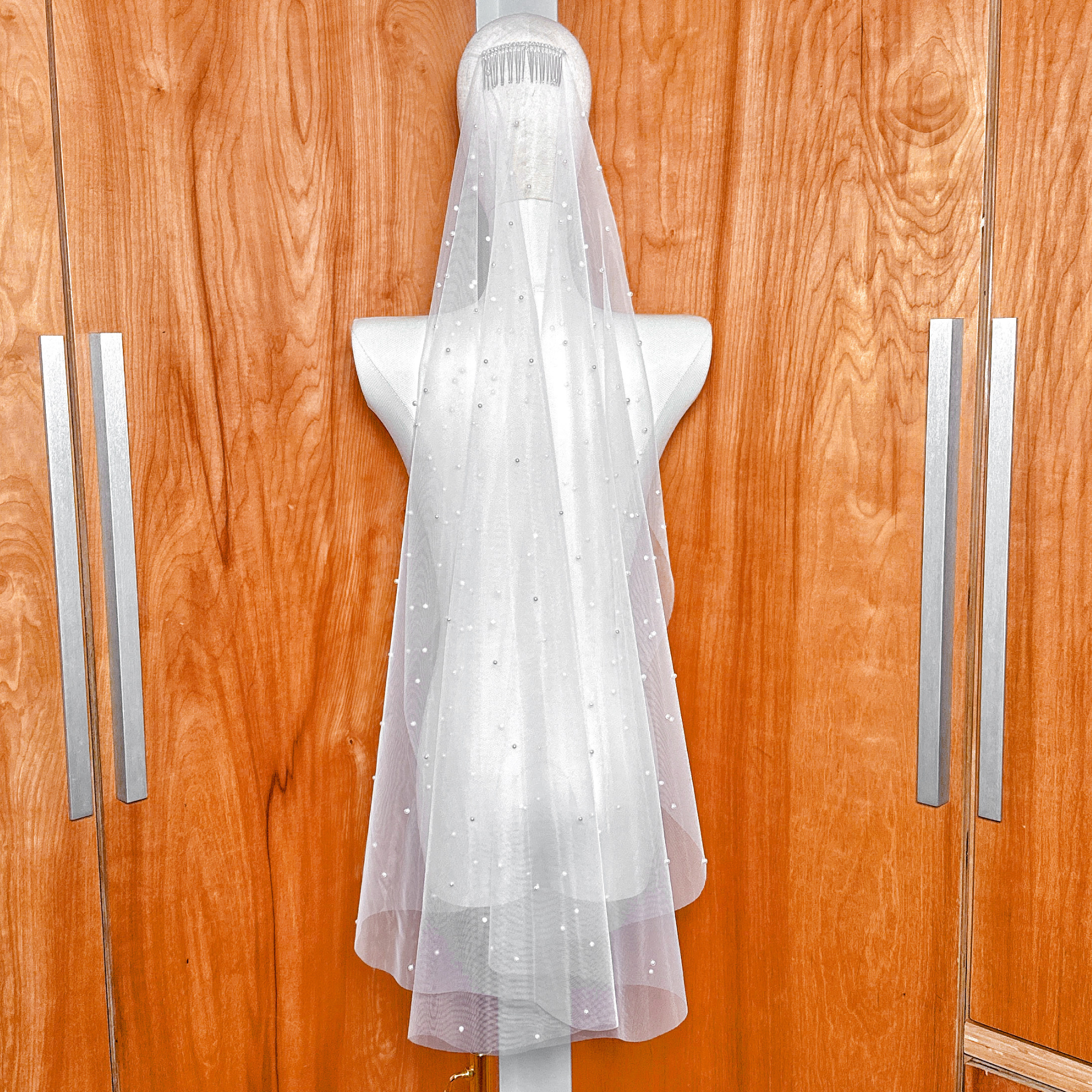 Back view of a scattered pearl fingertip wedding veil showcasing the "starlit" effect of pearls distributed across the lower half of the tulle.