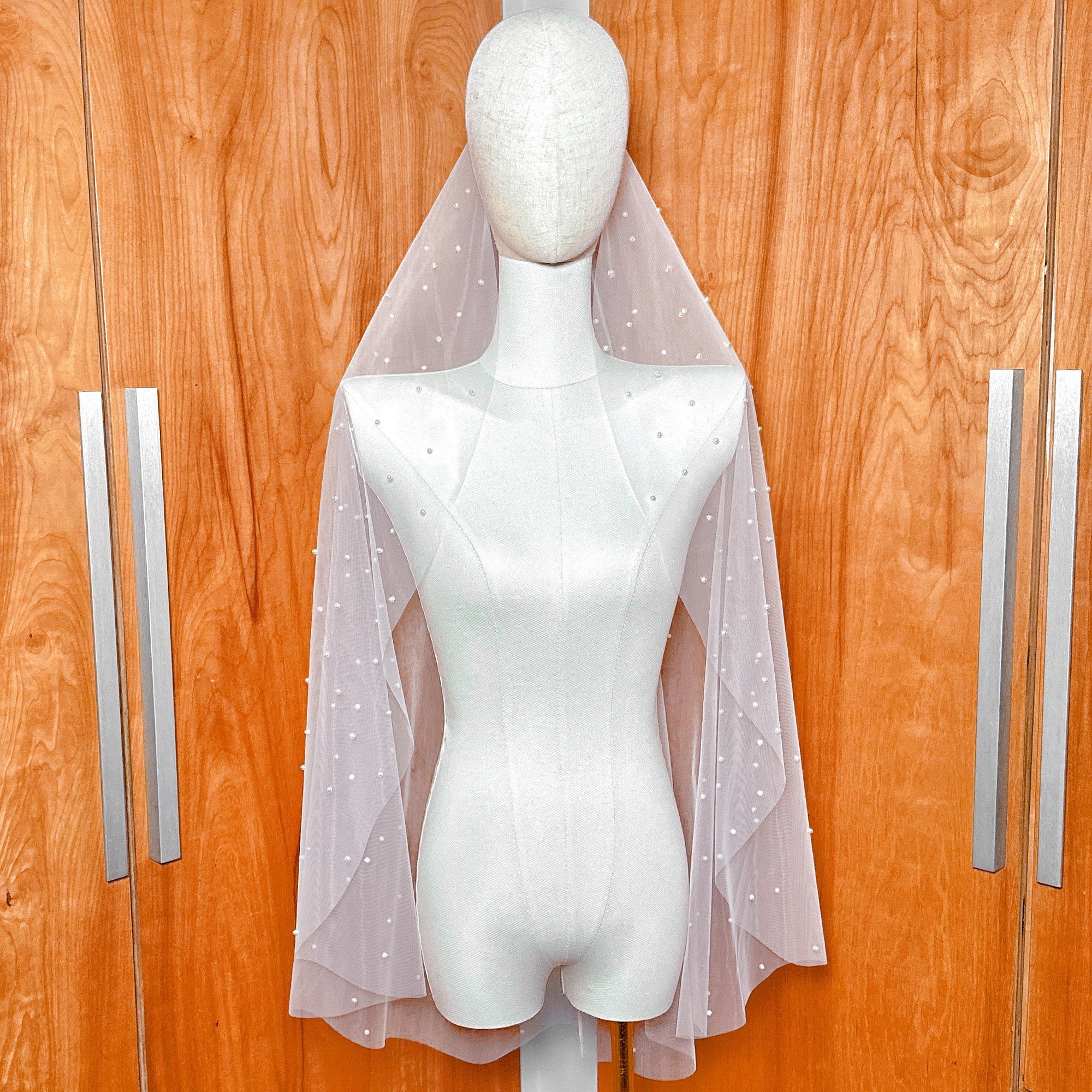 Front view of a ivory scattered pearl fingertip wedding veil showing a delicate cascade of pearls on soft bridal tulle.