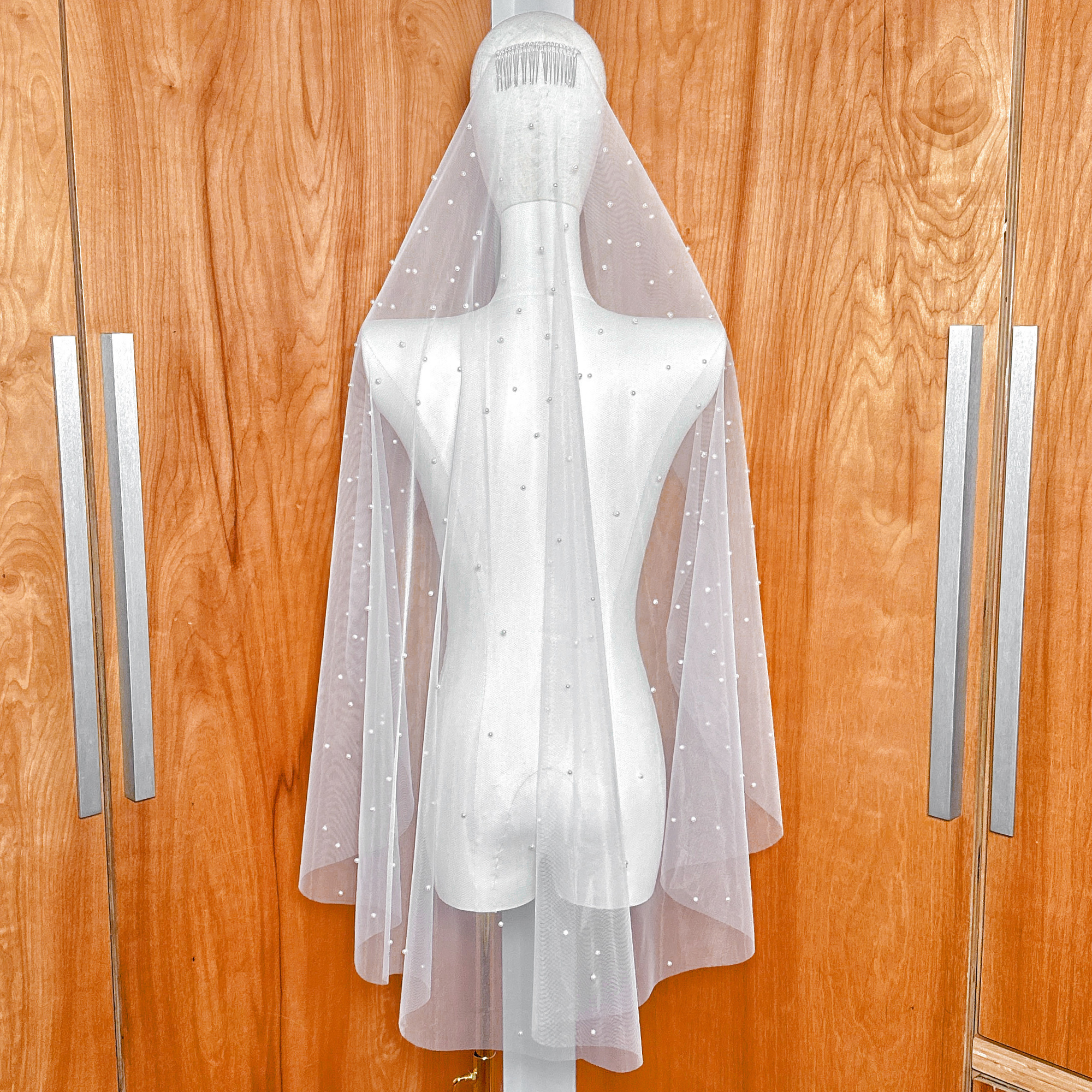 Top view of the metal comb attachment on a scattered pearl fingertip wedding veil, showing high pearl density near the headpiece.