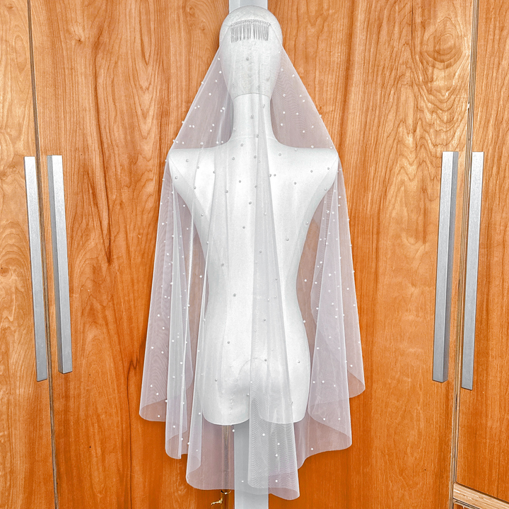 Top view of the metal comb attachment on a scattered pearl fingertip wedding veil, showing high pearl density near the headpiece.