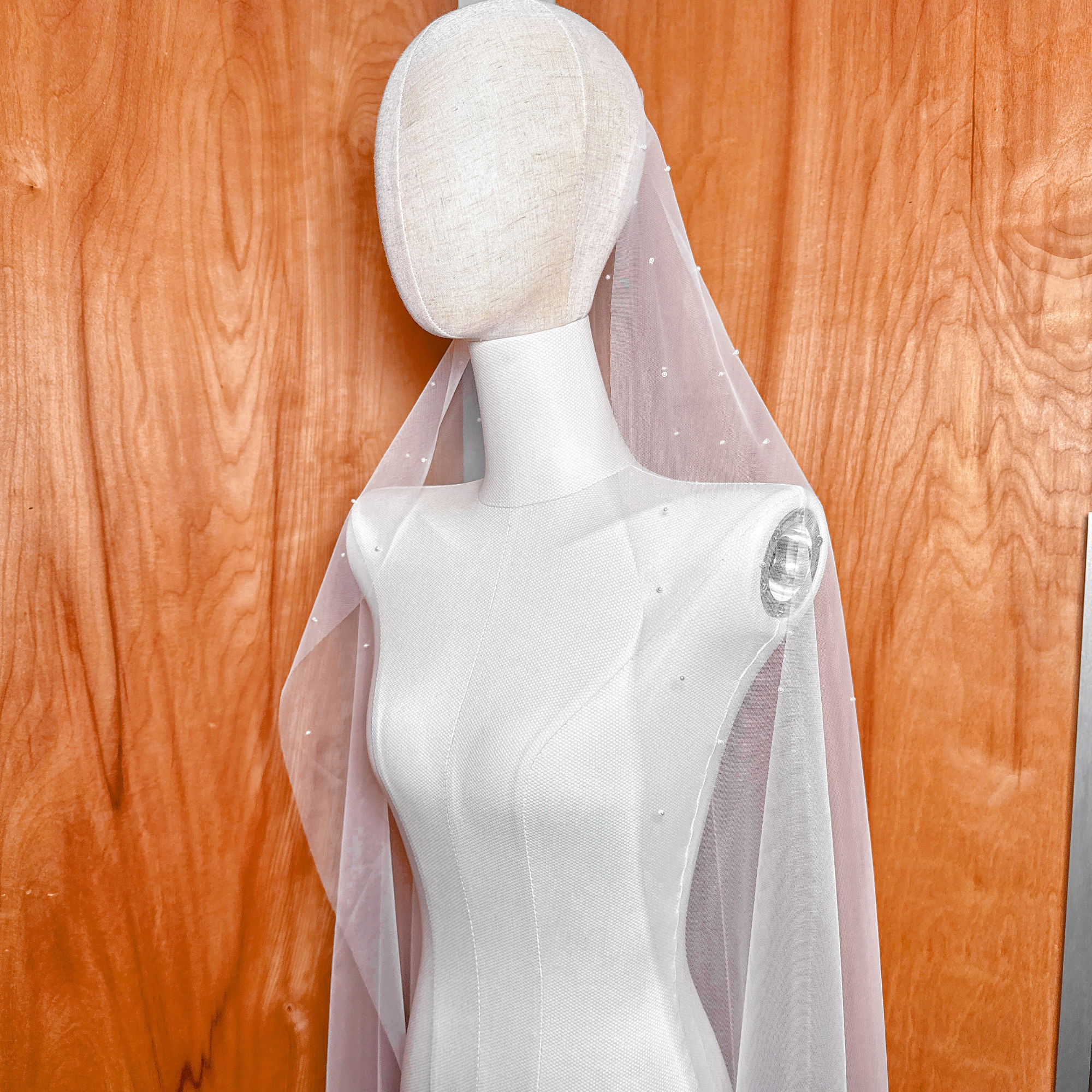 Timeless mantilla-style wedding veil embellished with shimmering scattered pearls, designed in a versatile waltz length.