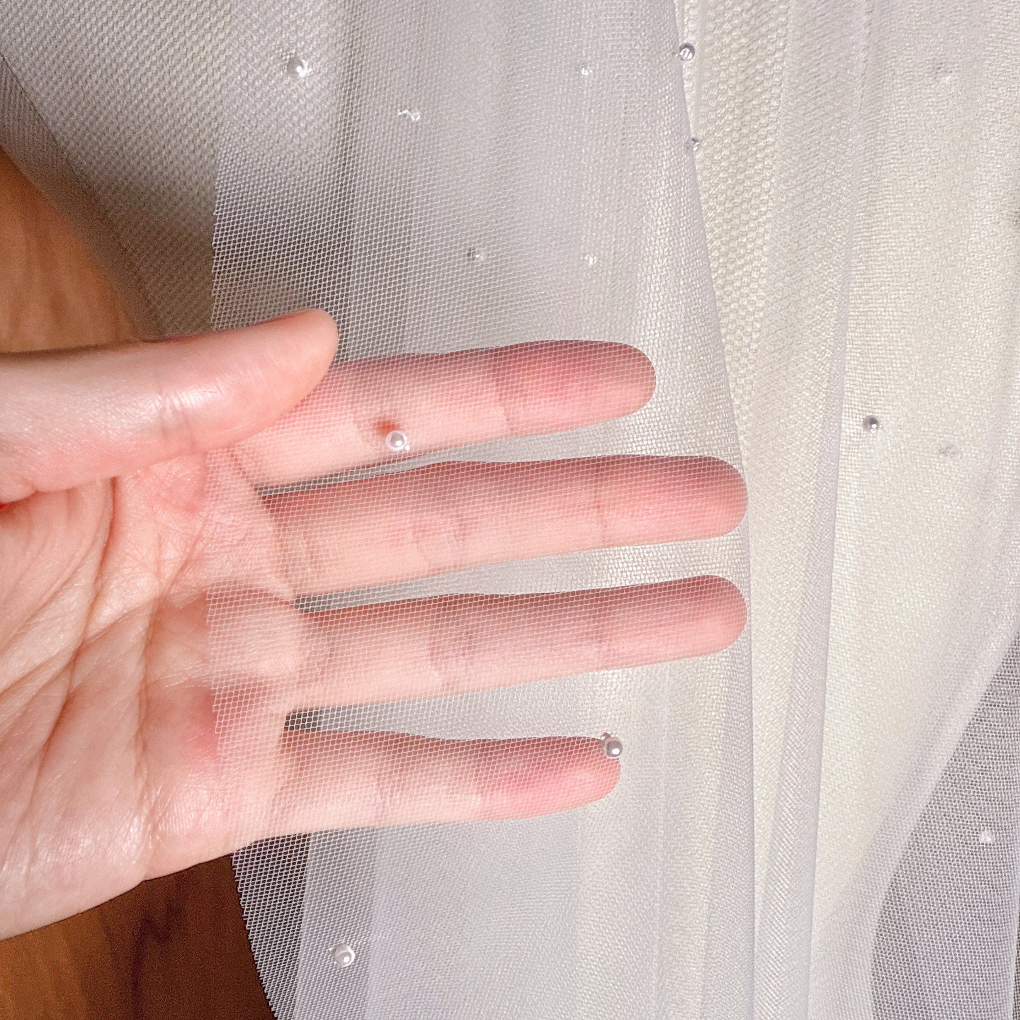 Detailed image of the scattered pearls on a waltz length mantilla-style bridal veil.