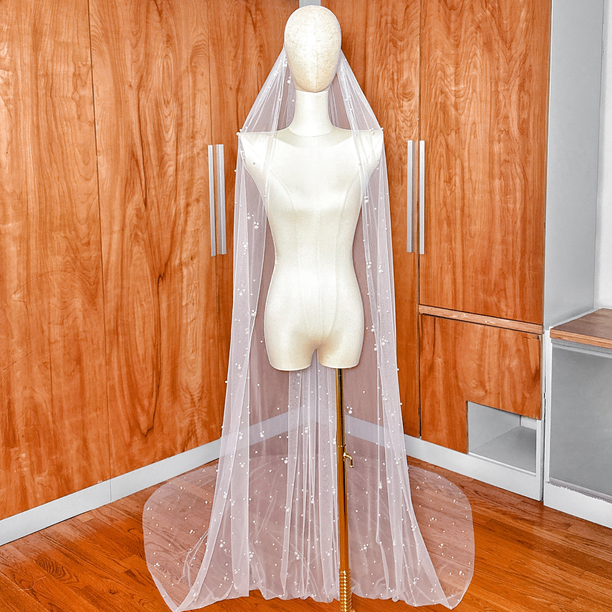 A long ivory scattered pearl wedding veil in cathedral length draped elegantly to show the delicate pearl placement.