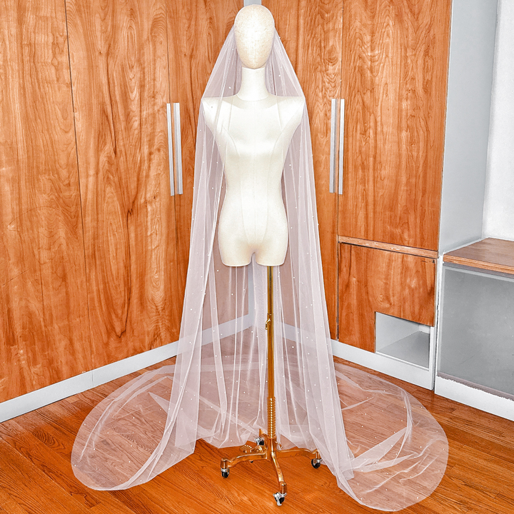A full-length view of a 118-inch cathedral wedding veil featuring elegantly scattered pearls on ivory tulle.