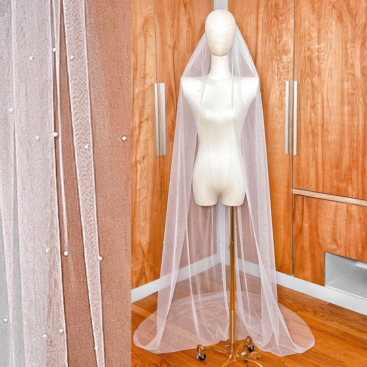 A chapel length scattered pearl wedding veil made of soft ivory tulle, showing the full drape of the single-tier design.