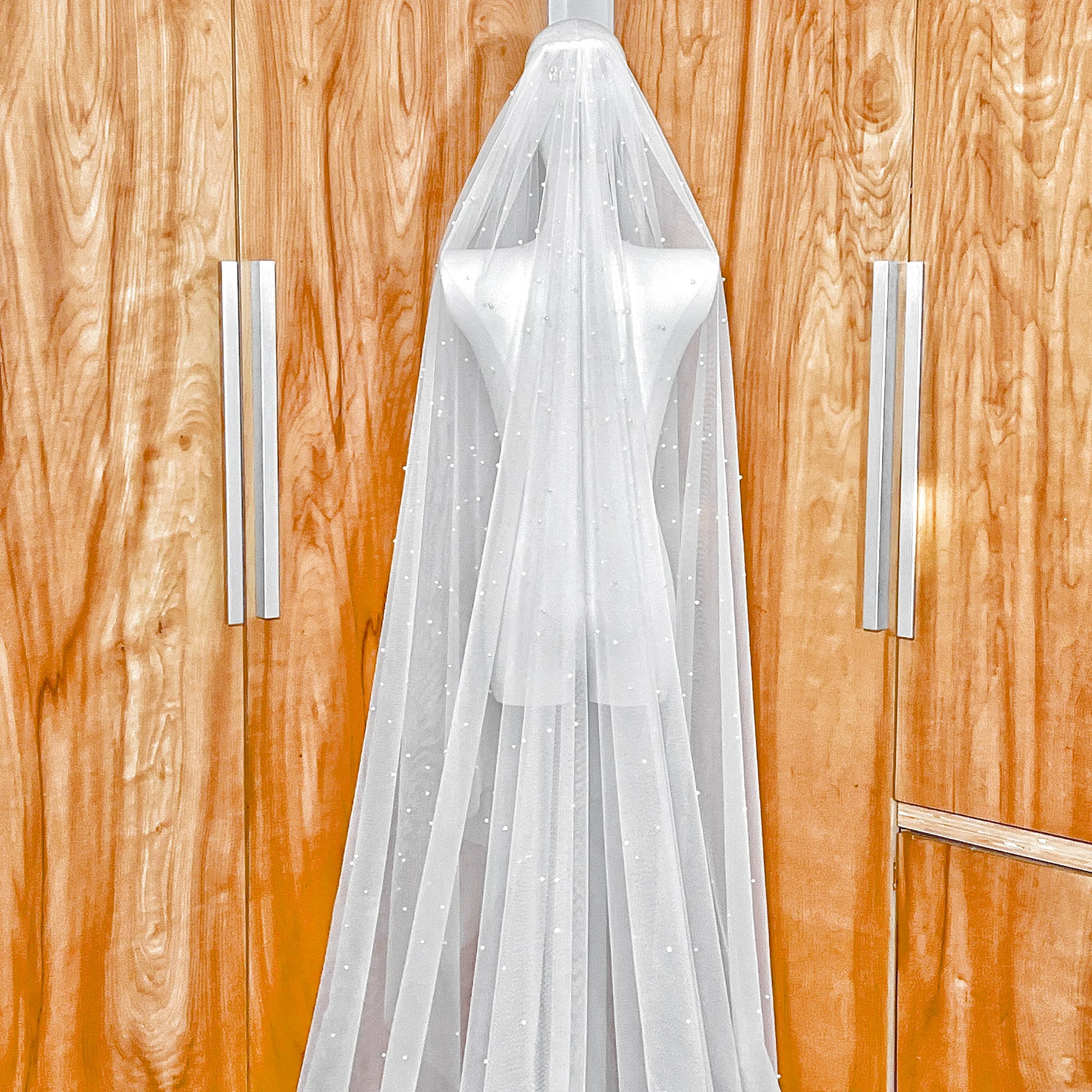 Cascading scattered pearl wedding veil showing the secure metal comb attachment and top-layer pearl distribution.
