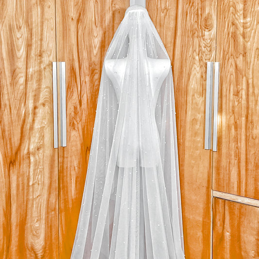 Cascading scattered pearl wedding veil showing the secure metal comb attachment and top-layer pearl distribution.