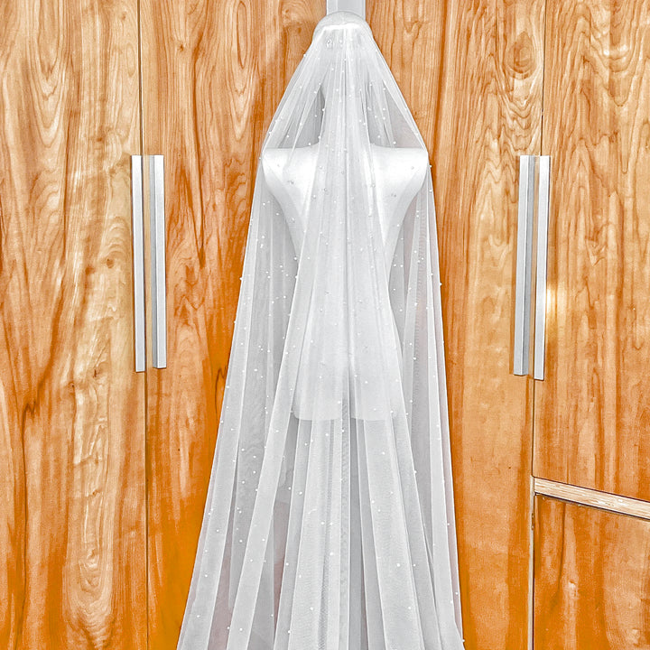 Cascading scattered pearl wedding veil showing the secure metal comb attachment and top-layer pearl distribution.