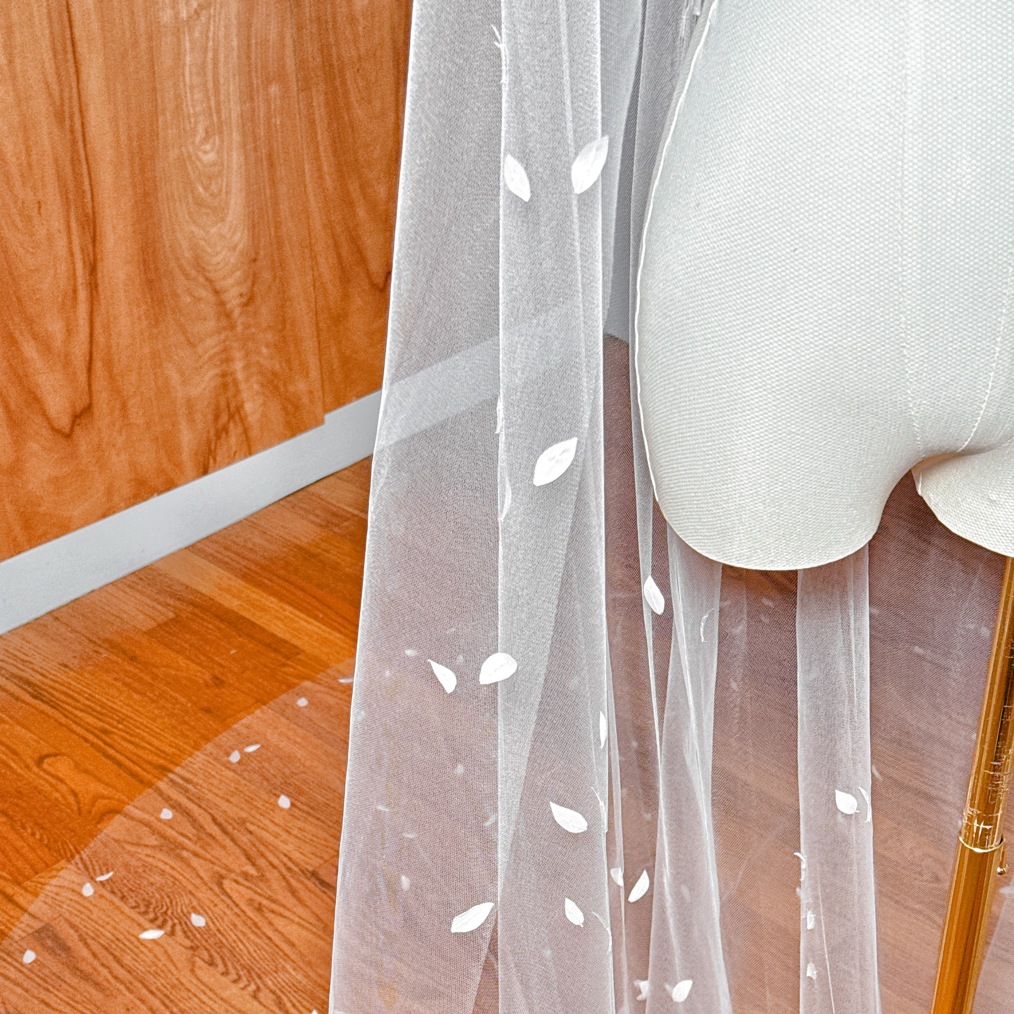 Ethereal and sheer 3D silk petal veil in cathedral length draped over a mannequin torso.