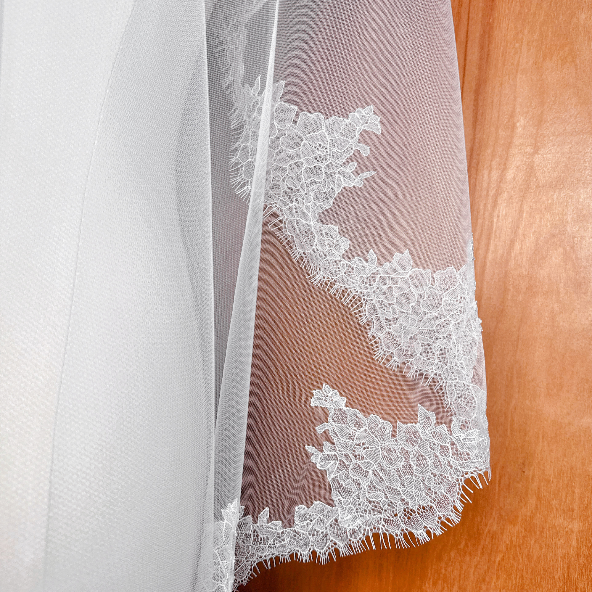 Sheer bridal tulle mantilla veil with Chantilly lace edging in a 40-inch fingertip length on a mannequin bust.
