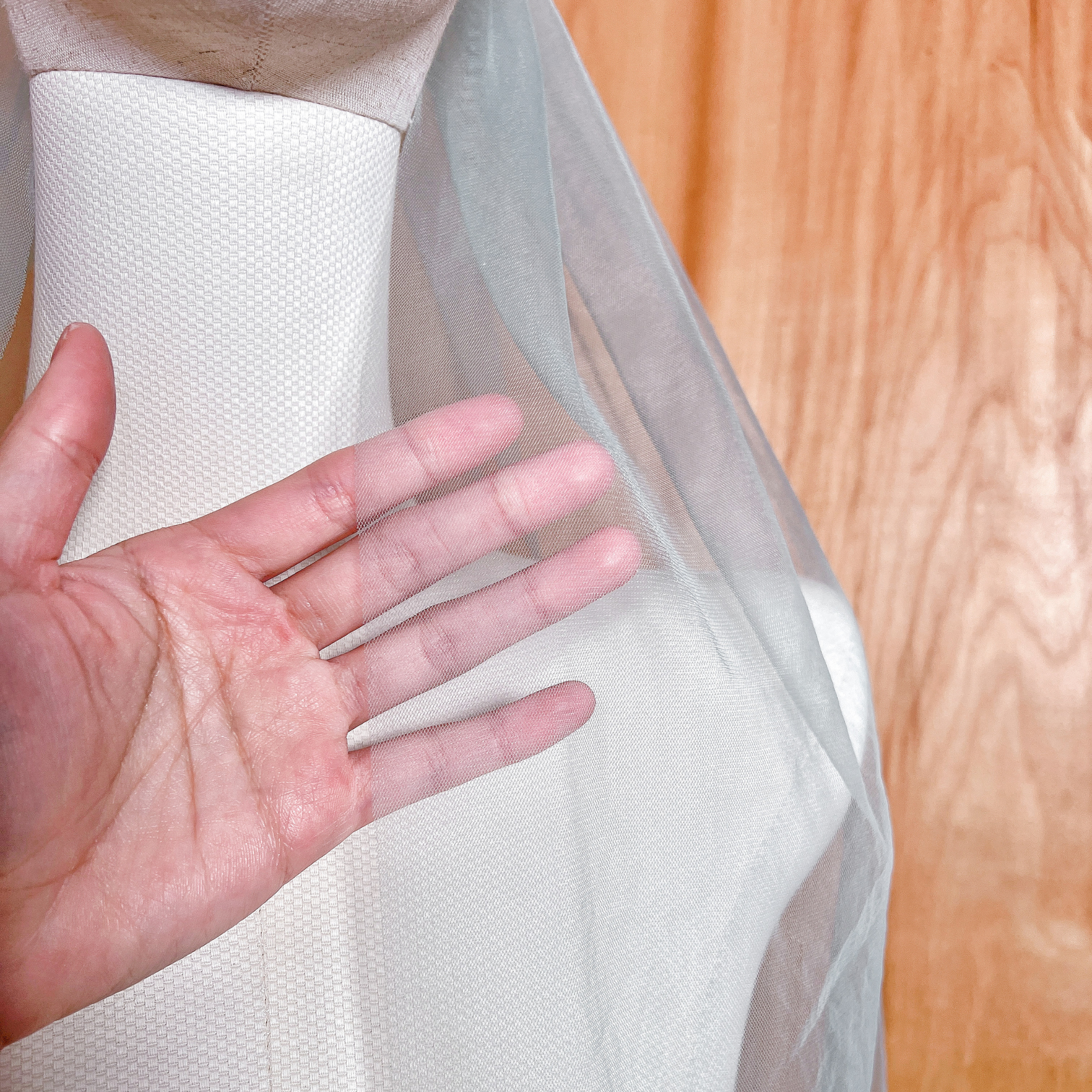 Close-up of a sheer sage green wedding veil in fingertip length showcasing the soft tulle fabric.