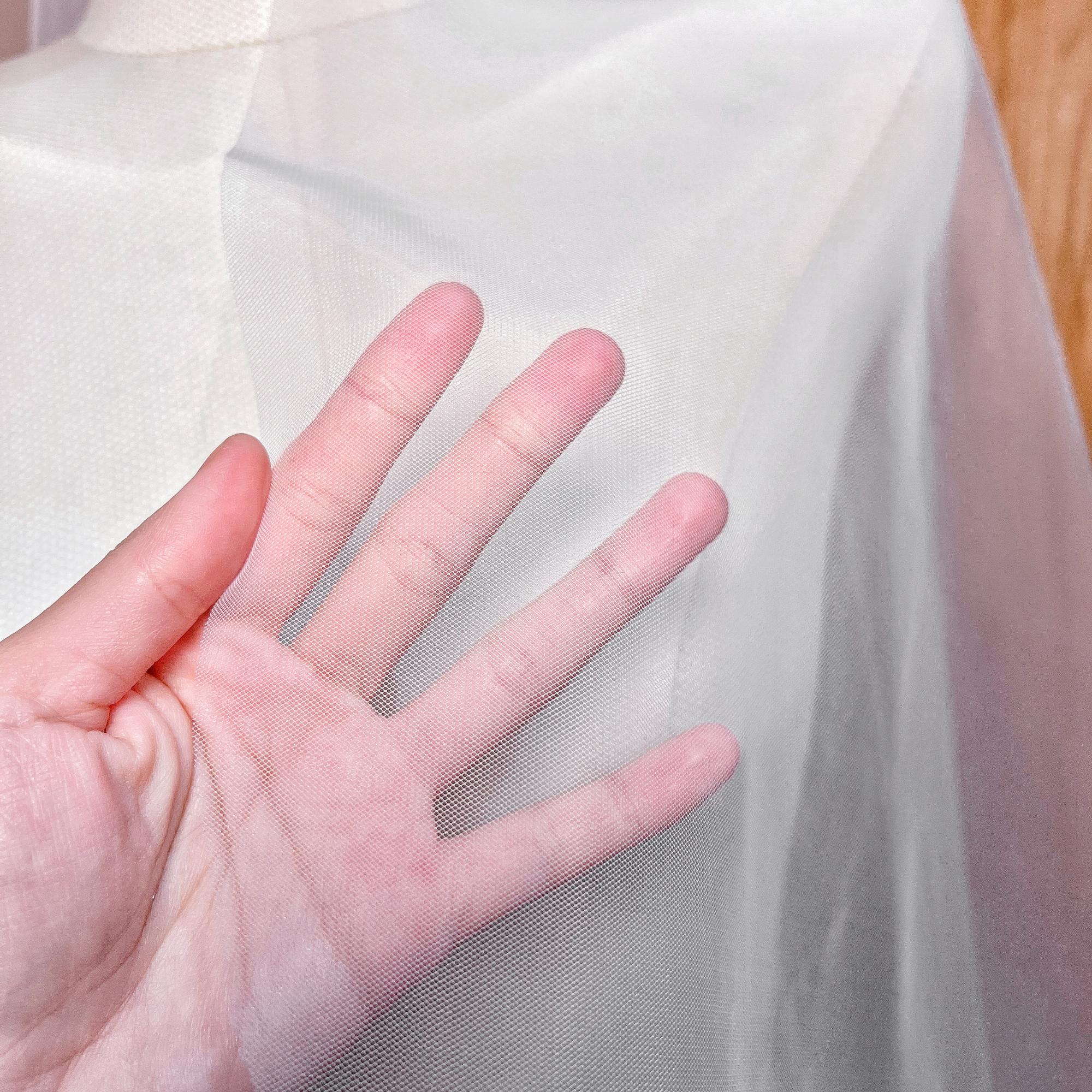 Close-up of the delicate sheer tulle and modern raw edge detail on a cascade knee-length veil.