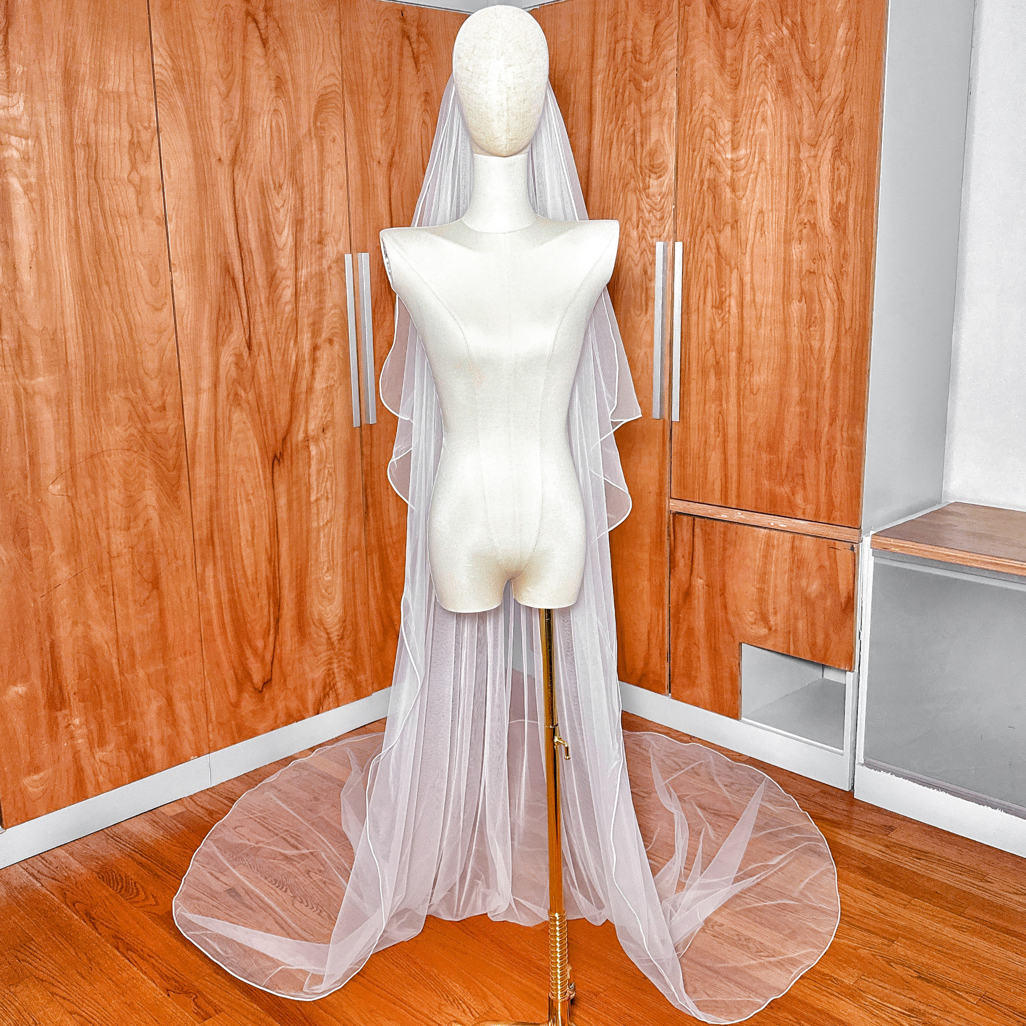 Sheer bridal tulle fabric of a cathedral length cascade wedding veil with premium corded edging.
