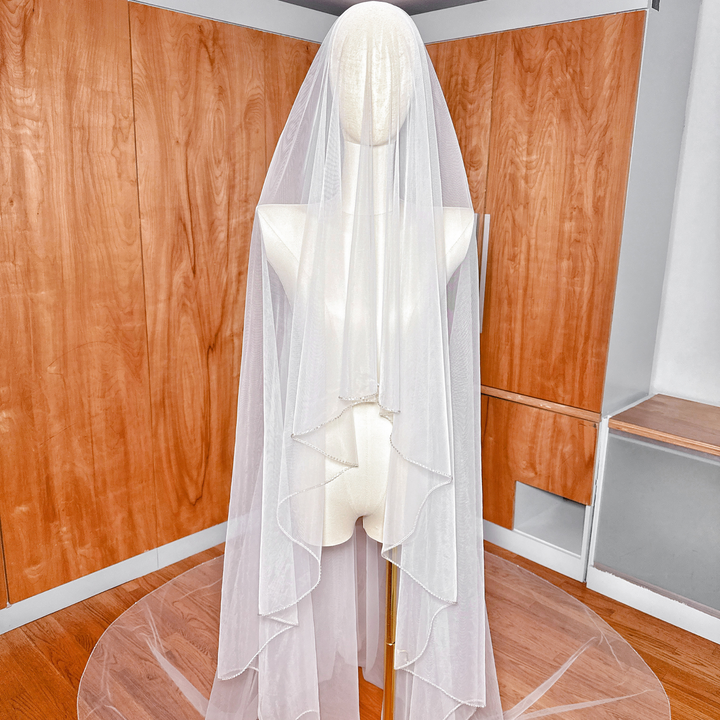 Close-up showcasing the lightweight, sheer premium tulle fabric of a two-tier cathedral length wedding veil with rhinestone edge.