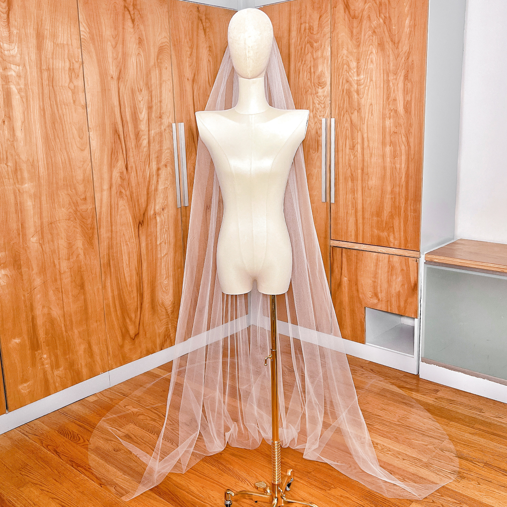 Detailed shot of the lightweight, sheer texture of a simple cathedral tulle wedding veil with a classic raw edge design.