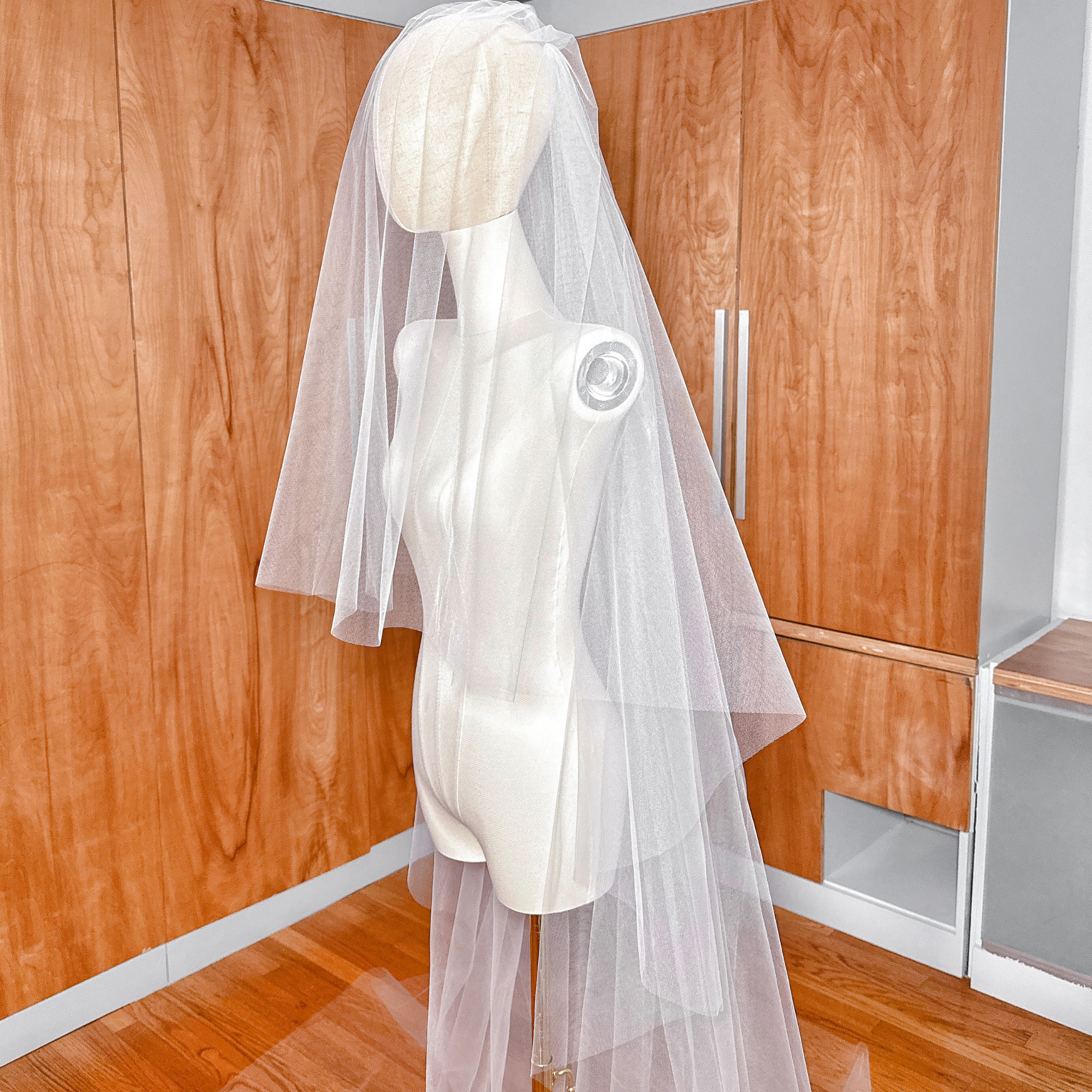 Sheer cathedral wedding veil in two-tier tulle with a simple raw edge for a minimalist bridal look.