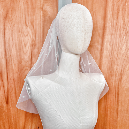 Front view of a short pearl veil in shoulder length, featuring scattered pearls on soft ivory tulle.