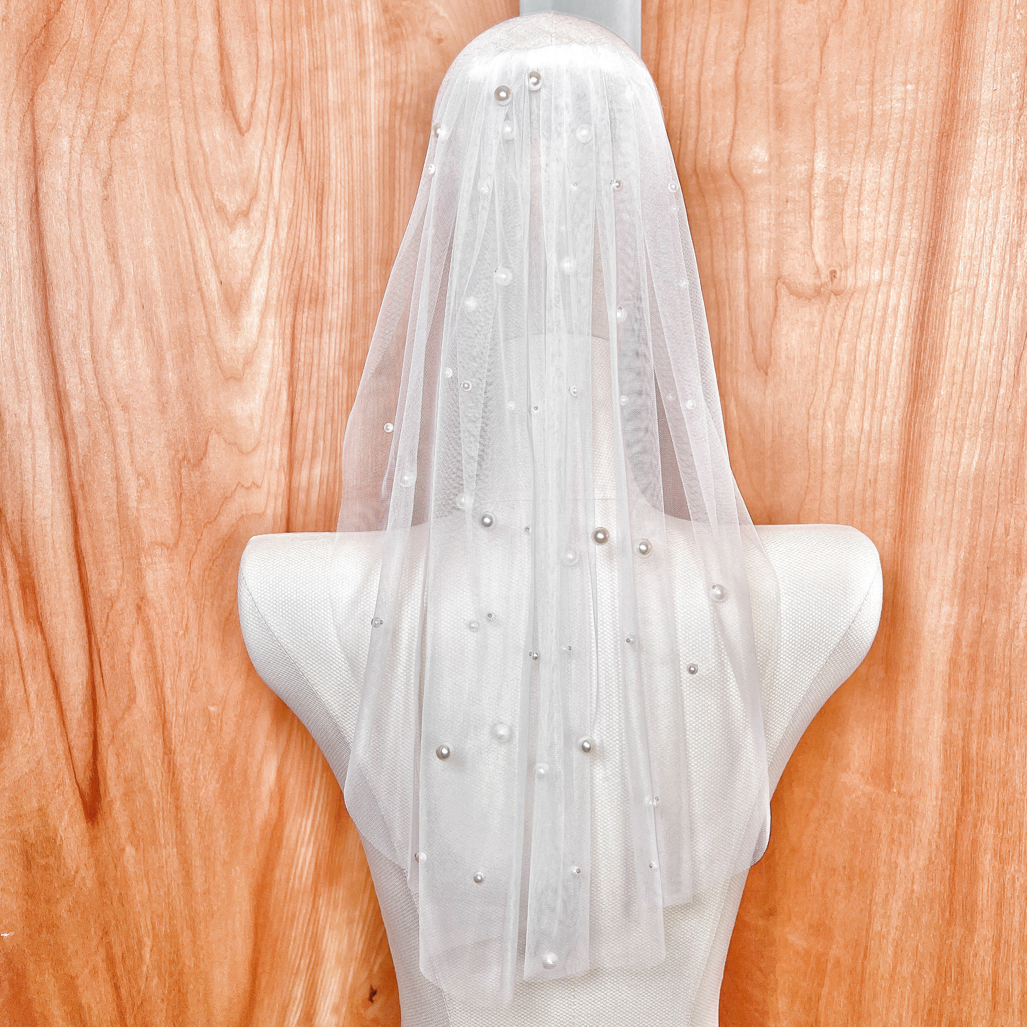 Close-up detail of the short pearl veil's shoulder length tulle and hand-applied pearl accents.