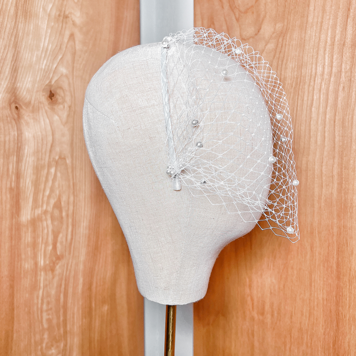 Side profile of a vintage style pearl birdcage wedding veil showing how the netting contours and fits.