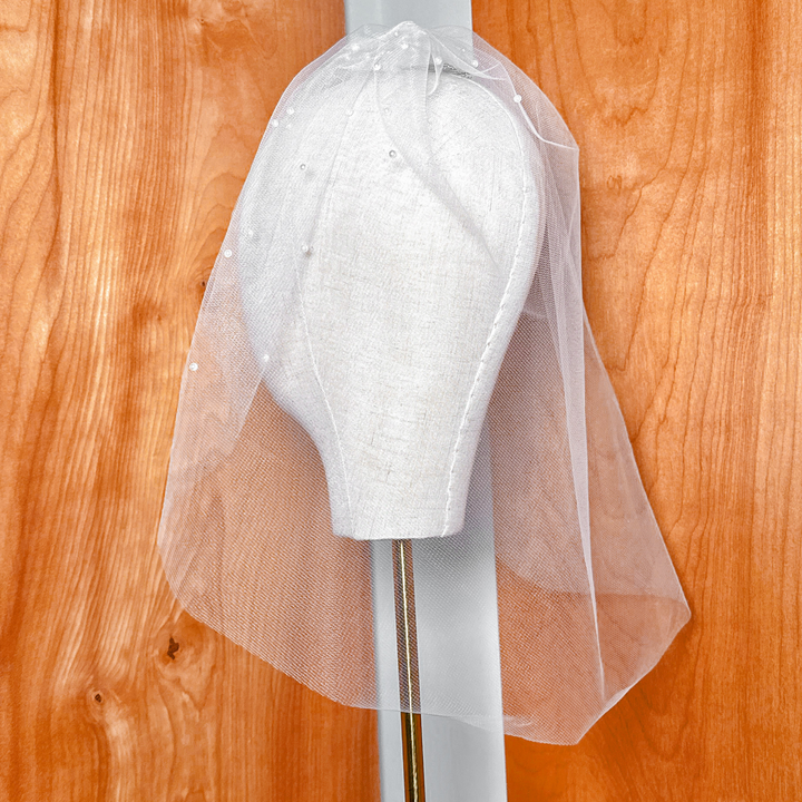 Side view of a sheer pearl birdcage wedding veil showing gathering and comb attachment.
