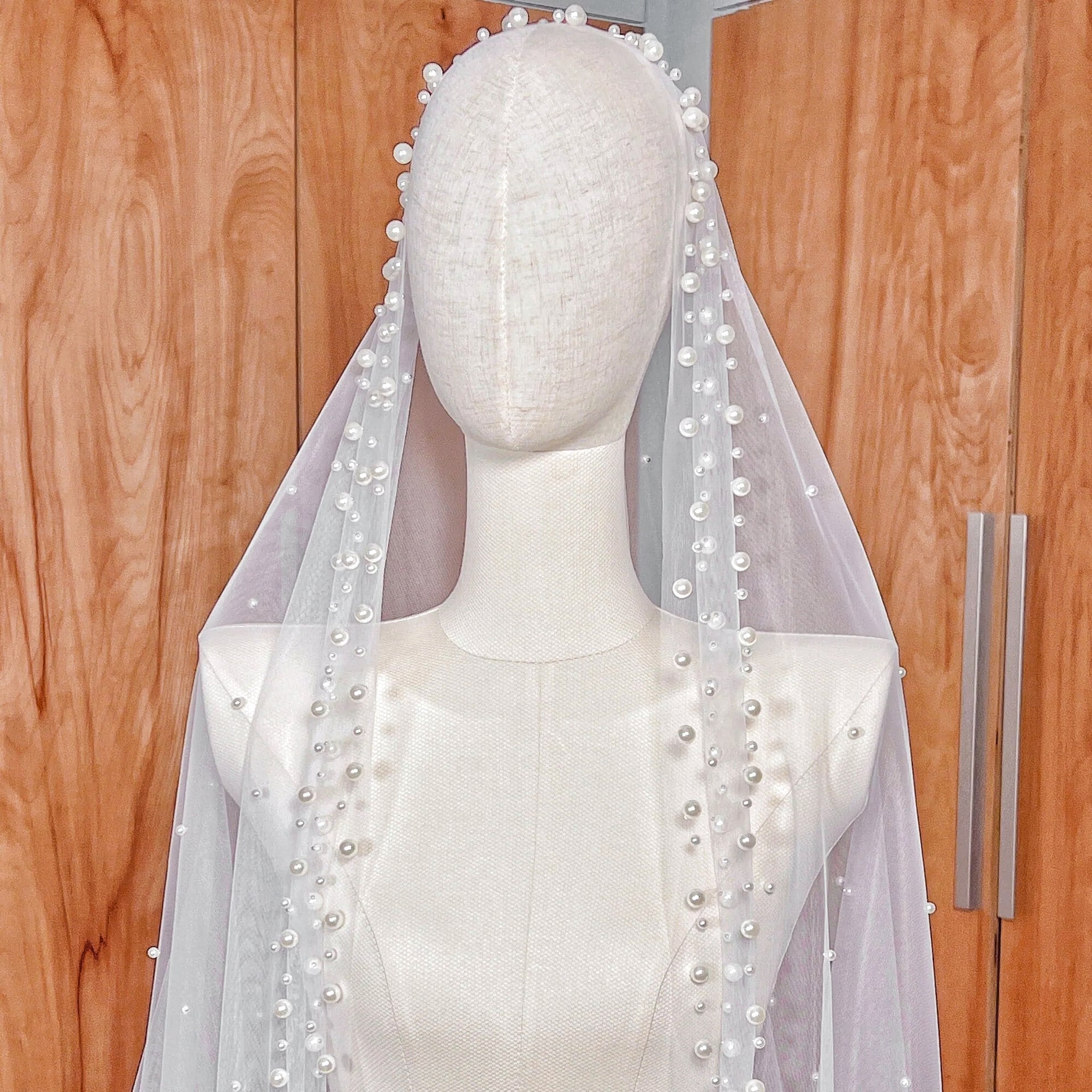 Side profile of the scattered pearl edge mantilla wedding veil in cathedral length shown on a mannequin to display the drape.